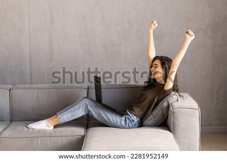 Woman sit on sofa put pc on lap clenched fists scream with joy while read great news on laptop. Gambler celebrate online auction bet victory. Got incredible offer sincere emotions of happiness concept Royalty-Free Stock Photo #2281952149