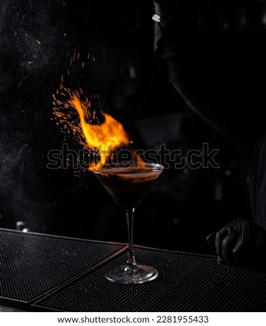 Bartender with fiery drink and black background
