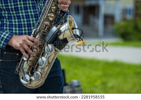 street saxophonist plays the saxophone outdoors. summer day street musician close-up of hands and saxophone keys