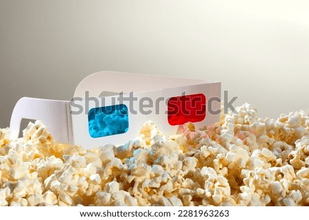 Cyan and red glasses for 3D movies over a pile of popcorn.
