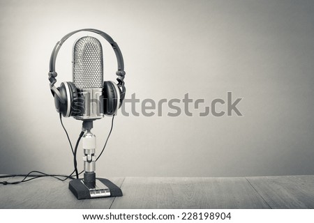 Retro studio ribbon microphone with headphones on table. Vintage old style greyscale photo