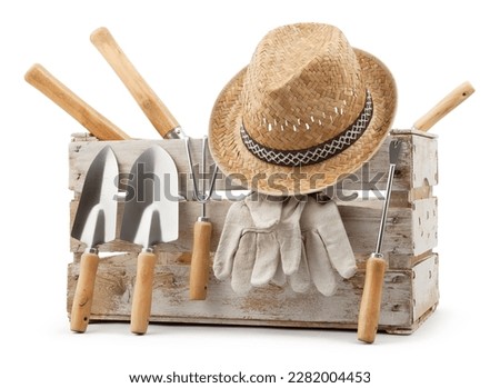 Gardening tools set, wooden crate with aluminum garden kit tools, Trowel with wooden handle, straw hat and protective gloves, isolated on white background. Concept of work or sale garden products Royalty-Free Stock Photo #2282004453