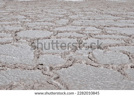 The salt flat features beautiful shapes formed by natural erosion and mineral deposits, creating a barren and arid environment.


