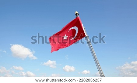Turkish flag flutters in wind against blue sky with white clouds. Flag on stern of sea ferry in Istanbul.