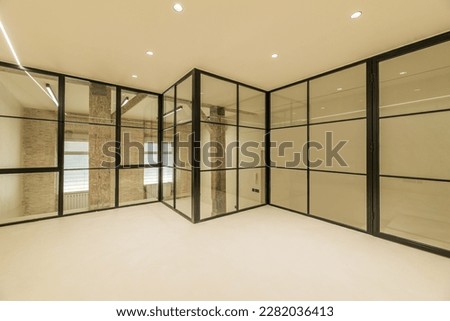 Loft apartment with vintage wooden beams and pillars, exposed brick walls, glass partitions with black metal frames, smooth white concrete floors and electric radiators Royalty-Free Stock Photo #2282036413