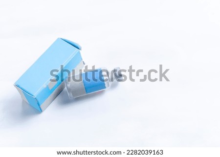 Medical glass vial bottle with blue box on white background. Selective focus. Vaccination concept.