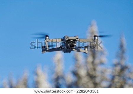Drone shooting winter landscape from air. Controlled quadcopter hovering above snowy forest. Close up shot of drone.