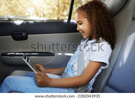 Happy, road trip and a child in a car with a tablet for a movie, cartoons or video. Smile, travel and a girl sitting in a vehicle with tech, streaming online and enjoying a film for entertainment