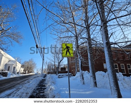 A crosswalk sign above a snowy area on a winter day.