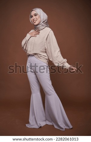 Full length portrait of hijab girl smiling. Pretty muslim girl. Beautiful asian muslimah woman model posing on dark background studio. Stylish Muslim female fashion lifestyle  concept.