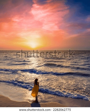 Seascape at  sunrise with beautiful sky. Woman on the beach. Young woman in a yellow fluttering dress on seashore. The girl looks at the magical sunrise.  Above Top view. Vertical banner #uniquesself Royalty-Free Stock Photo #2282062775