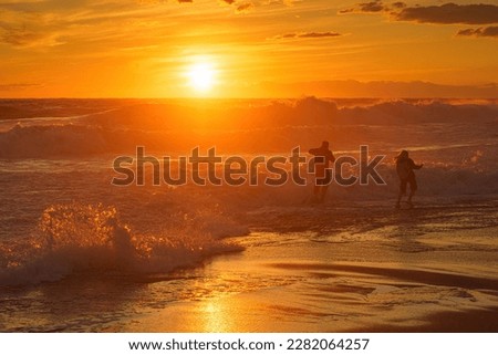 Dangerous games. Two people play in the waves at sunset. Storm, Mediterranean Sea, Turkey