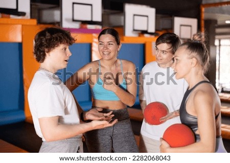 Cheerful young people in suitable clothes conversing friendly in modern trampoline area