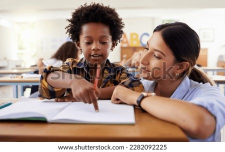 Teacher, learning and helping black kid in classroom for knowledge, studying or assessment. Question, development and boy or student with woman for education pointing in notebook in kindergarten. Royalty-Free Stock Photo #2282092225