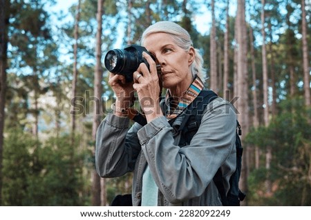 Hiking, nature and woman taking photos with a camera, capturing memories and view in a forest. Travel, tourist and an elderly lady taking pictures in a woods or the mountains for a photography hobby Royalty-Free Stock Photo #2282092249
