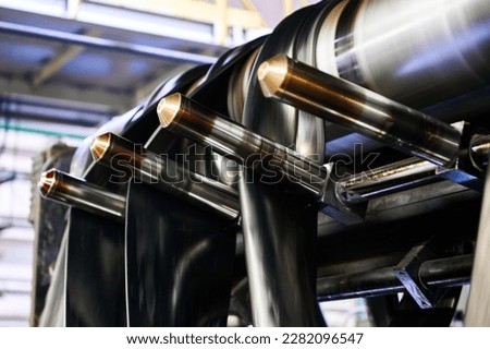 Black rubber ribbons rolled by tool at compound calendering Royalty-Free Stock Photo #2282096547