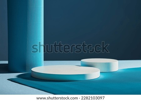 Front view of two white round empty podiums on dark blue background. Minimal art background with copy space for cosmetics product presentation