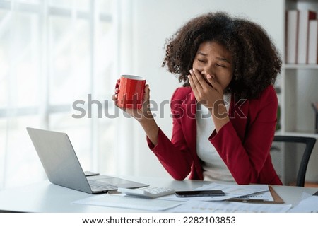 Elegant african american businesswoman in formal attire sitting with hot cup of coffee during break to relax and drinking anti-drowsy coffee while working on laptop recording meeting in office. Royalty-Free Stock Photo #2282103853