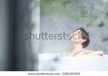 A woman relaxing in a bathtub at a ryokan or hotel. For images of hot springs, etc. Royalty-Free Stock Photo #2282105503