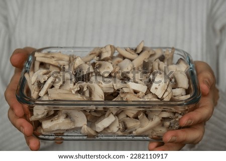 Unrecognizable woman showing into camera frozen food sliced mushrooms champignon homemade. Harvesting concept. Stocking up vegetables for winter storage
