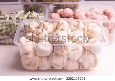 Frozen vegetables and semi-finished meat products in plastic containers on a white plate. meatballs, dumplings, chopped beans