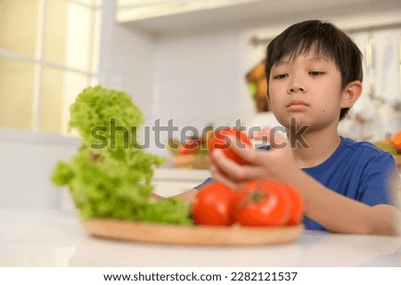 Asian boy feeling bored , unhappy to eat vegetables , health care concept 
