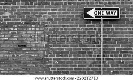 one way street sign in front of brick wall