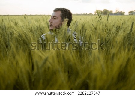 young adult man in hidden wheat field looking to the side at sunset. #uniqueSSelf Royalty-Free Stock Photo #2282127547
