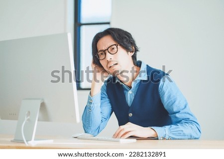 Young man struggling in front of computer Royalty-Free Stock Photo #2282132891