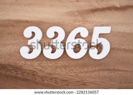 White number 3365 on a brown and light brown wooden background.
