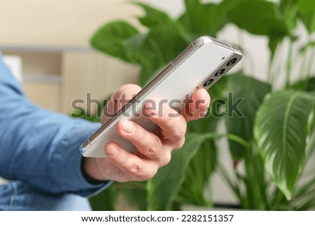 Close up image of male hands using smartphone in home interior, search or social media concept, man typing sms message to his friends
