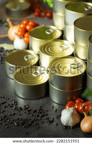 canned food many tin jars stacked in columns beatuful arranged on black surface tomatoes garlic onion pepper close up for advertising magazines industrial 