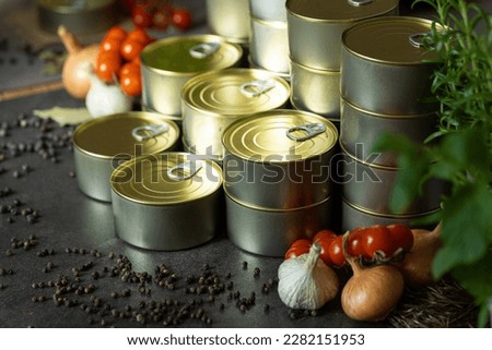 canned food many tin jars stacked in columns beatuful arranged on black surface tomatoes garlic onion pepper close up for advertising magazines industrial 