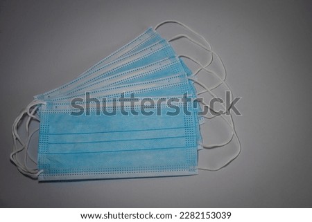 Blue surgical masks with rubber ears straps  stacked in layers on gray background, Bacteria protection concept.