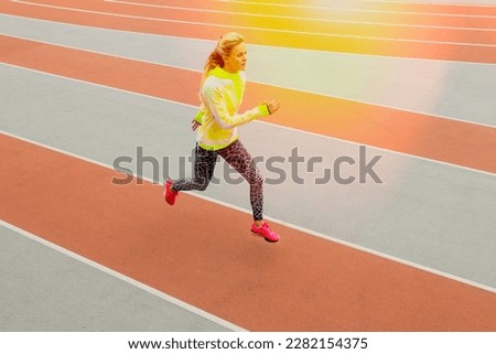 Top view of an athlete running on a treadmill. A young woman in a bright tracksuit. Competitions.Photo with toning