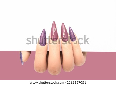 Female hand wih perfect beige stiletto manicure holding white paper on beige background. Template for postcard, advertising banner or message. Nails card design element.
