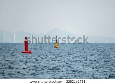 Marine red buoy in fairway. Navigational signs. Escorting ship to port. Floating yellow navigational buoy on blue sea. Marine signal buoy. Navigational Buoy marking a shipping channel