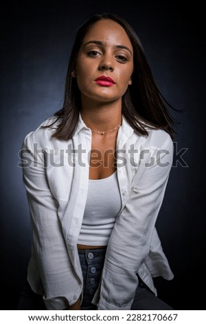 A pretty dark-haired girl posing for a fashion shoot in a studio. She is dressed in stylish jeans and a crop top, and her poses convey a sense of youthfulness and vitality.
