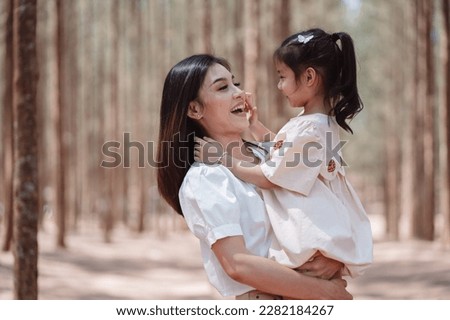 Happy family mother cute daughter enjoying love emotion together on grassy field in forest.