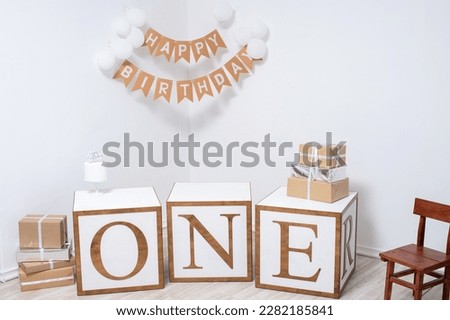 Decor in a white room for a birthday celebration with balloons, cubes and gifts