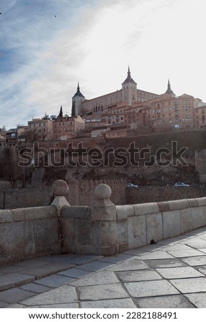 Alcántara bridge and the famous Alcázar fortrees at the medieval city of Toledo during sunset. Royalty-Free Stock Photo #2282188491