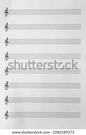 Sheet with empty staves for music notes and treble clef as background, top view Royalty-Free Stock Photo #2282189373