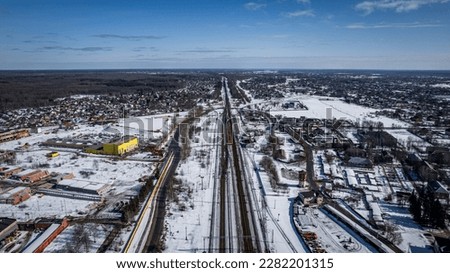 Railway tracks in a snowy village from a bird's eye view.