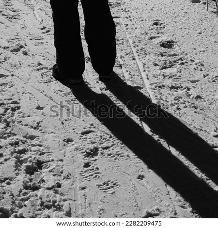 person standing on bright snow casting a long shadow