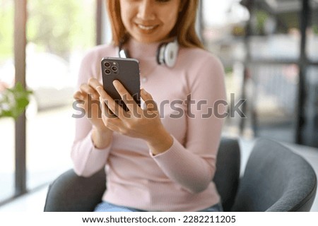 Close-up image of an attractive millennial Asian woman using her smartphone while resting in the coffee shop. chat, online shopping, mobile apps