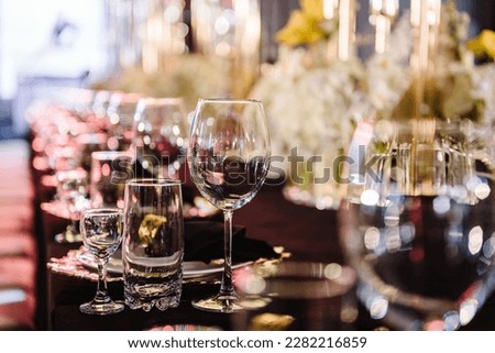 Wedding set up, dinner table reception. Serving, setting table. Plate and glass, stack, wineglass, luxury golden rich decor. Side view. Closeup. Birthday, baptism, event. Closeup details interior. Royalty-Free Stock Photo #2282216859