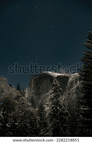 This photograph captures the stunning beauty of Half Dome at night, with the iconic rock formation illuminated by the stars and surrounding lights.