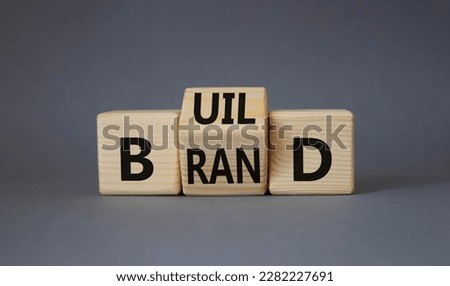 Build your brand symbol. Turned wooden cubes with words Build and Brand. Beautiful grey background. Build your brand and business concept. Copy space