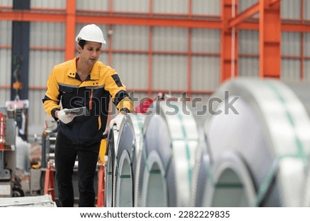 Metalwork manufacturing, warehouse of raw materials. Male factory worker inspecting quality rolls of metal sheet in factory during manufacturing process, wearing safety uniform, use digital tablet Royalty-Free Stock Photo #2282229835