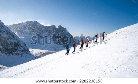 Process of hiking in Northern Norway, Lofoten Islands, Nordland, on the way to Ryten mountain and Kvalvika beach, with a groups of hikers, and mountains around, sunny winter day Royalty-Free Stock Photo #2282238153